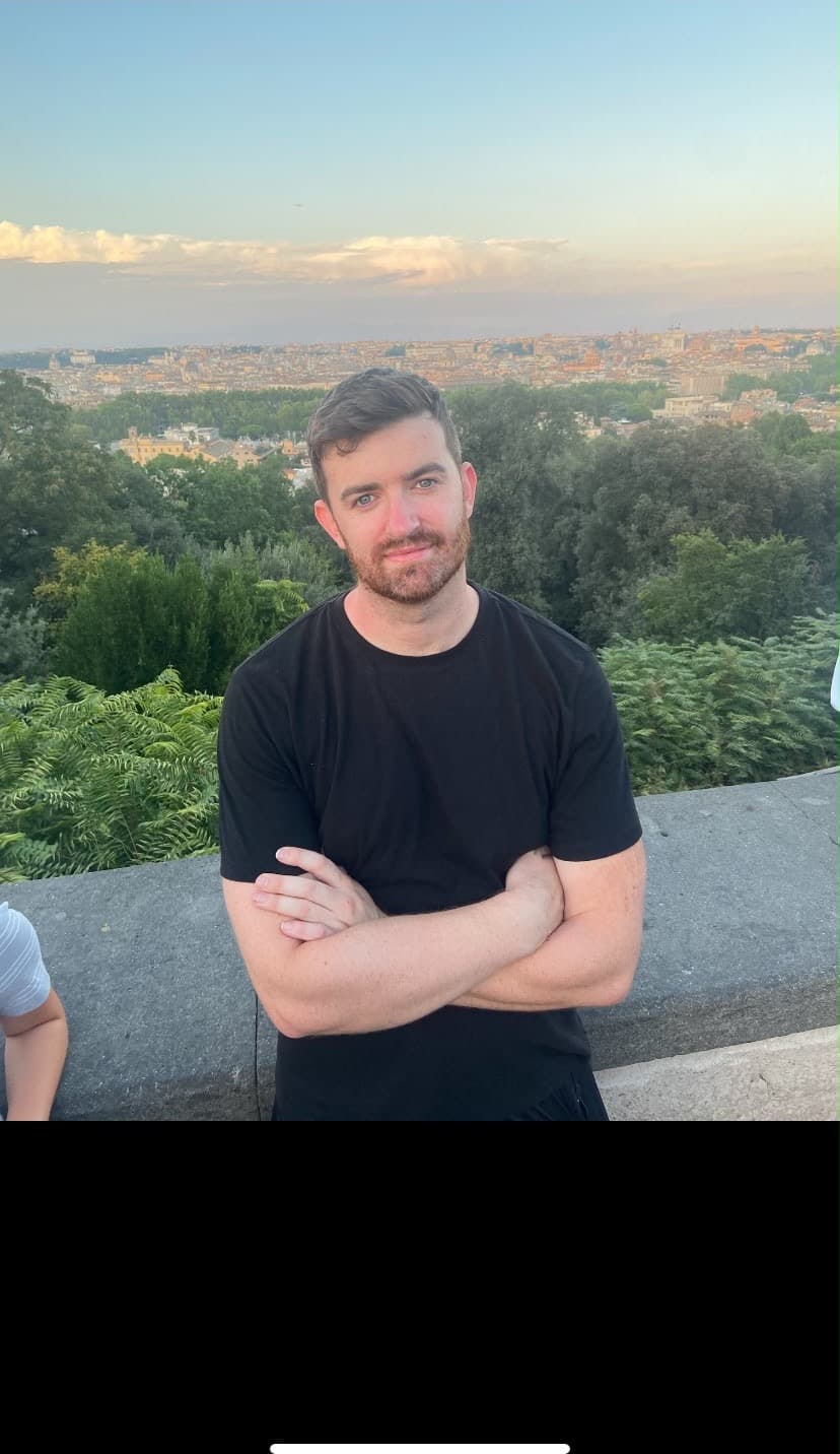 Conor, de brazos cruzados, en una terraza sobre una ciudad al atardecer